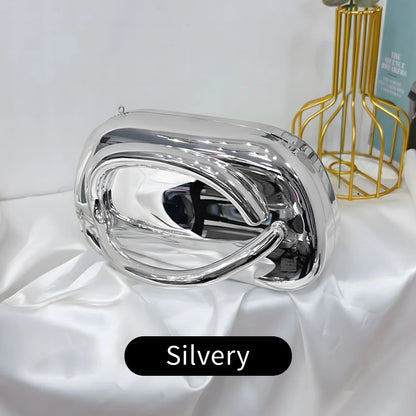 Silver Carauana Festival Clutch Bag on a white surface with a gold decorative item in the background