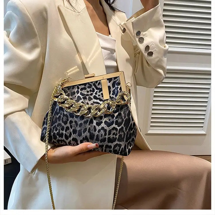 Person holding a leopard print handbag with gold chain detail