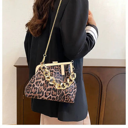 Person holding a Carauana_UNIU_Leopard_Clutch with gold chain detail