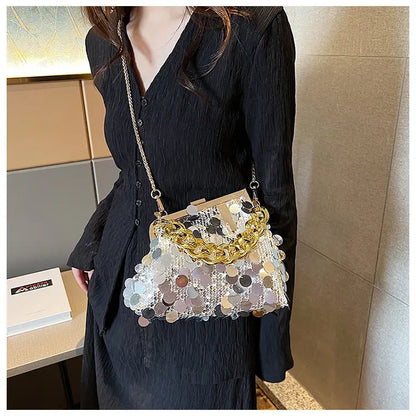 Person wearing a black outfit with a decorative handbag featuring gold chains and multicolored sequins.