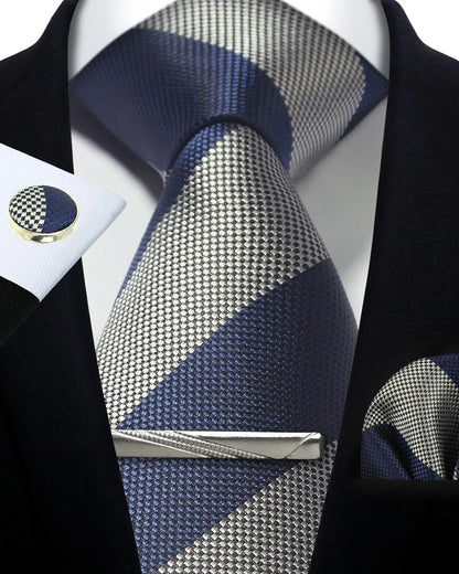 Navy and silver patterned tie with matching pocket square and cufflinks on a black suit.
