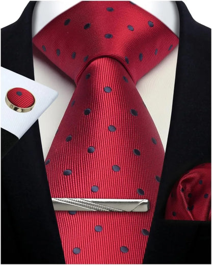 Red tie with black polka dots, silver tie clip, and matching cufflinks on a suit.