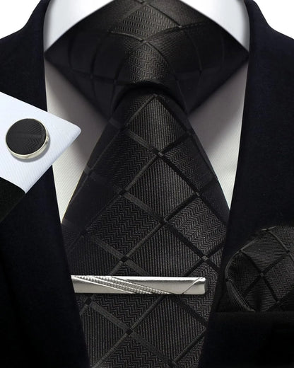 Black patterned tie with matching pocket square and cufflinks on a white shirt.