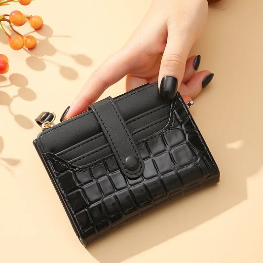 Black textured wallet held by a hand on a beige background